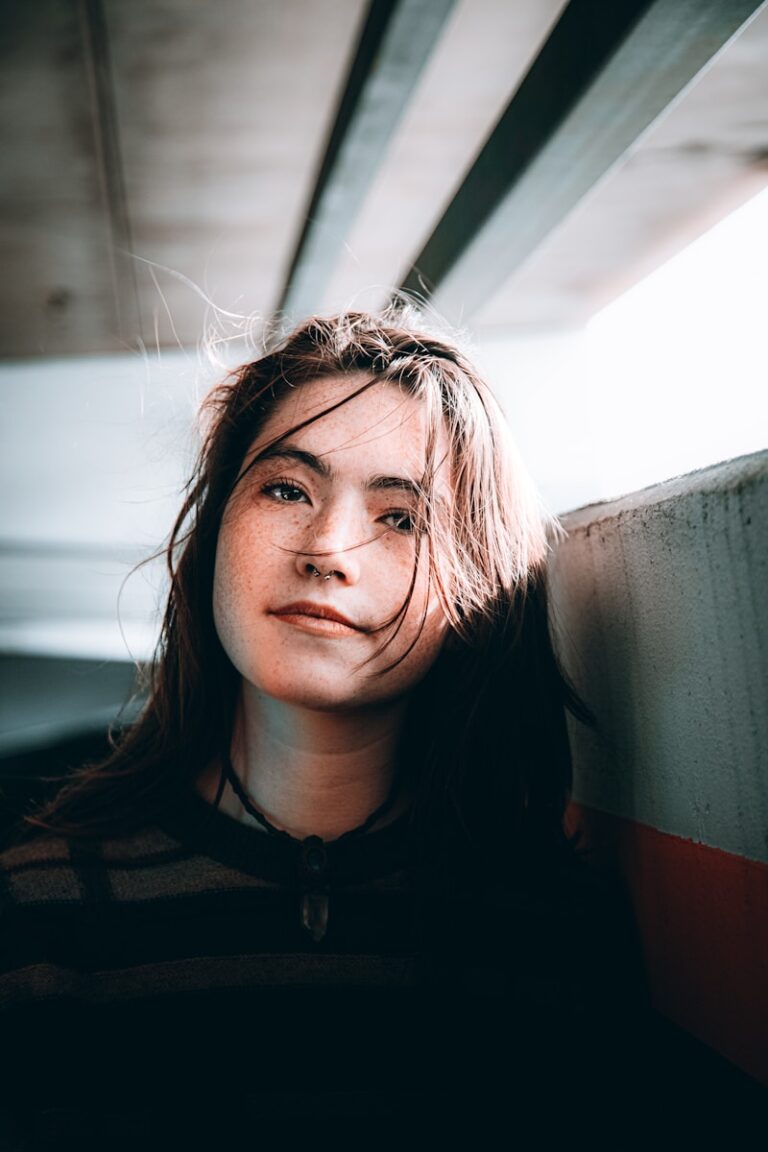 A woman leaning against a wall with her eyes closed