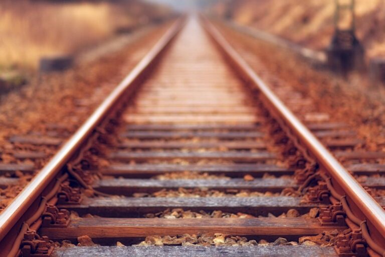 A detailed close-up view of railway tracks stretching into the distance surrounded by autumn colors.