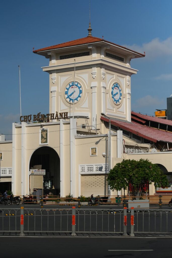 Iconic clock tower of Ben Thanh Market in Ho Chi Minh City with clear blue sky overhead.