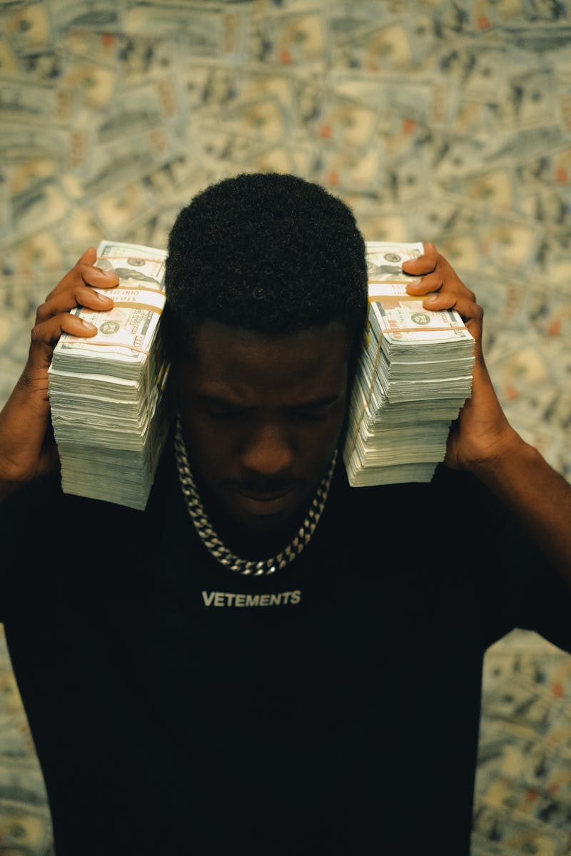 Man with cash stacks in luxury fashion shirt, exuding wealth and style.