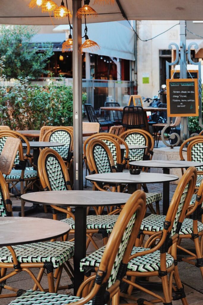 Explore the cozy outdoor seating in a quaint Avignon café, perfect for a relaxing day.