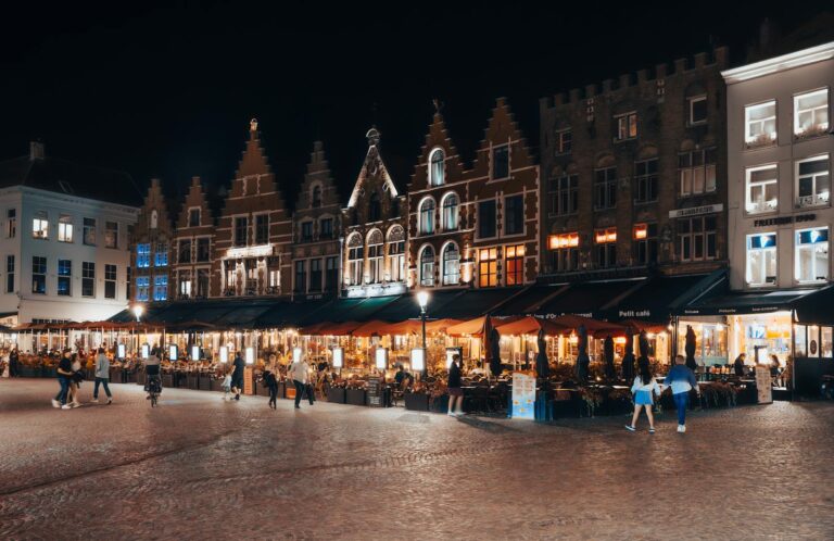 Explore the vibrant nightlife in Bruges with stunning medieval architecture, illuminated under night skies.