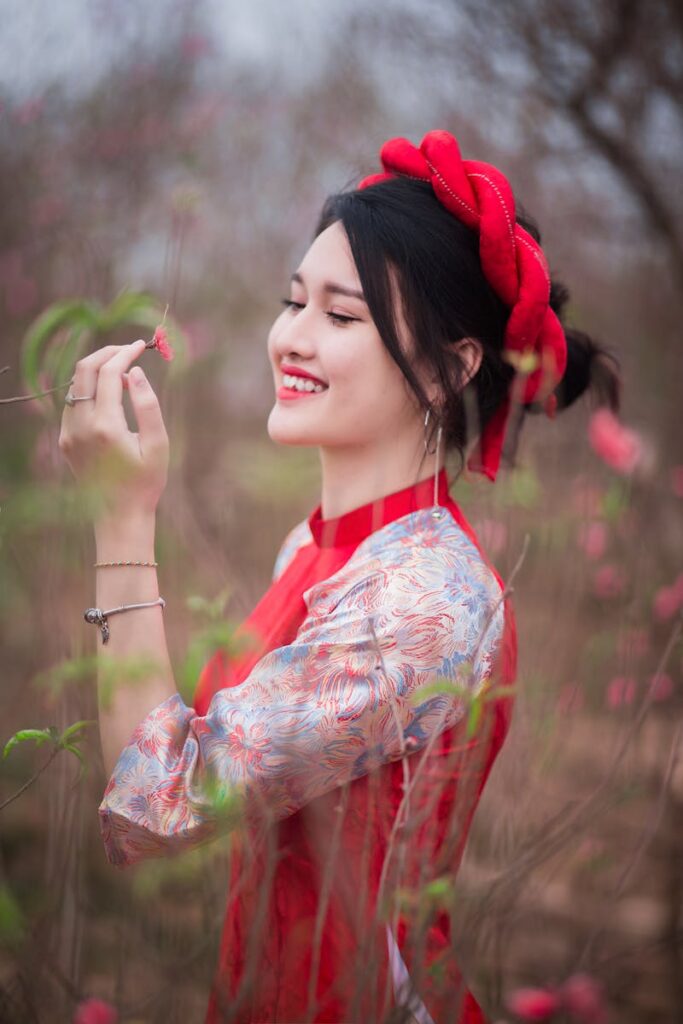Smiling young woman in traditional dress enjoying flowers in a spring field.