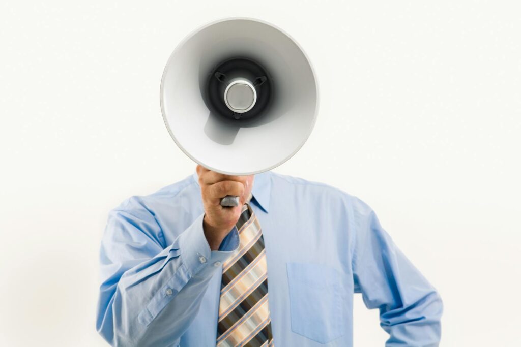 Businessman in blue shirt holding megaphone, symbolizing leadership and communication.