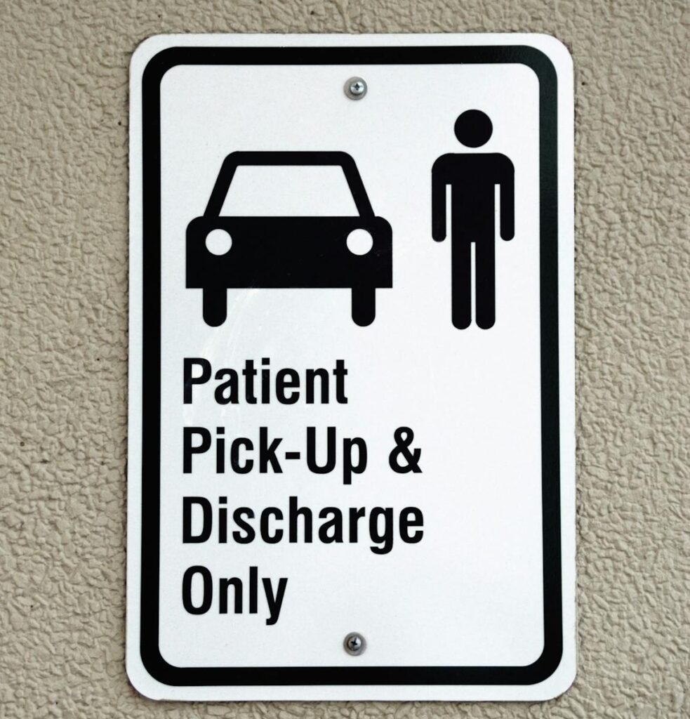 Sign indicating patient pick-up and discharge area at a healthcare facility.