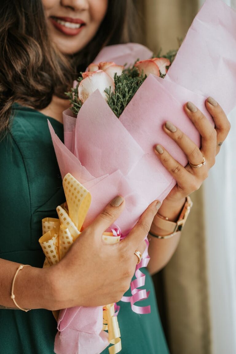 Close-up of woman holding a pink bouquet, smiling indoors.