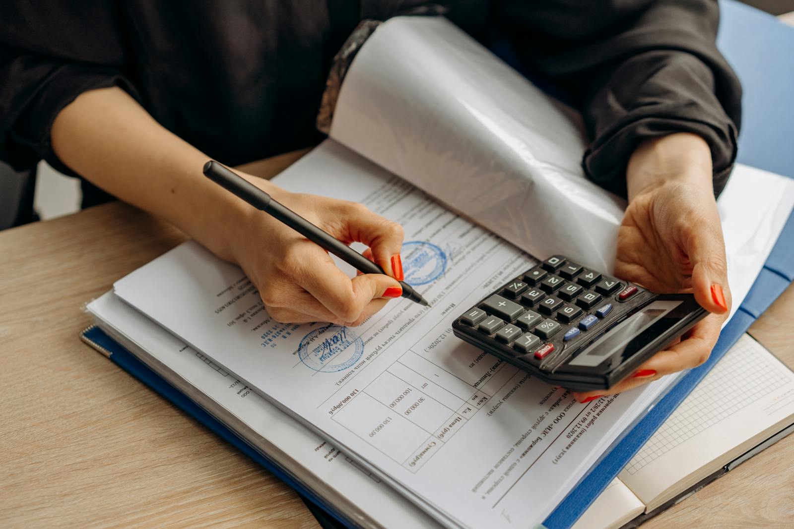 <strong>The Growing Epidemic of Online Scams in Vietnam: A Guide to Staying Safe </strong> An accountant using a calculator and signing paperwork, showcasing financial analysis.