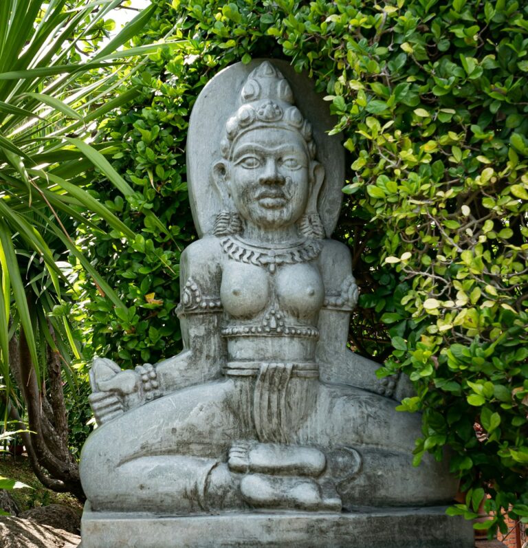 Gray concrete statue surrounded by green plants
