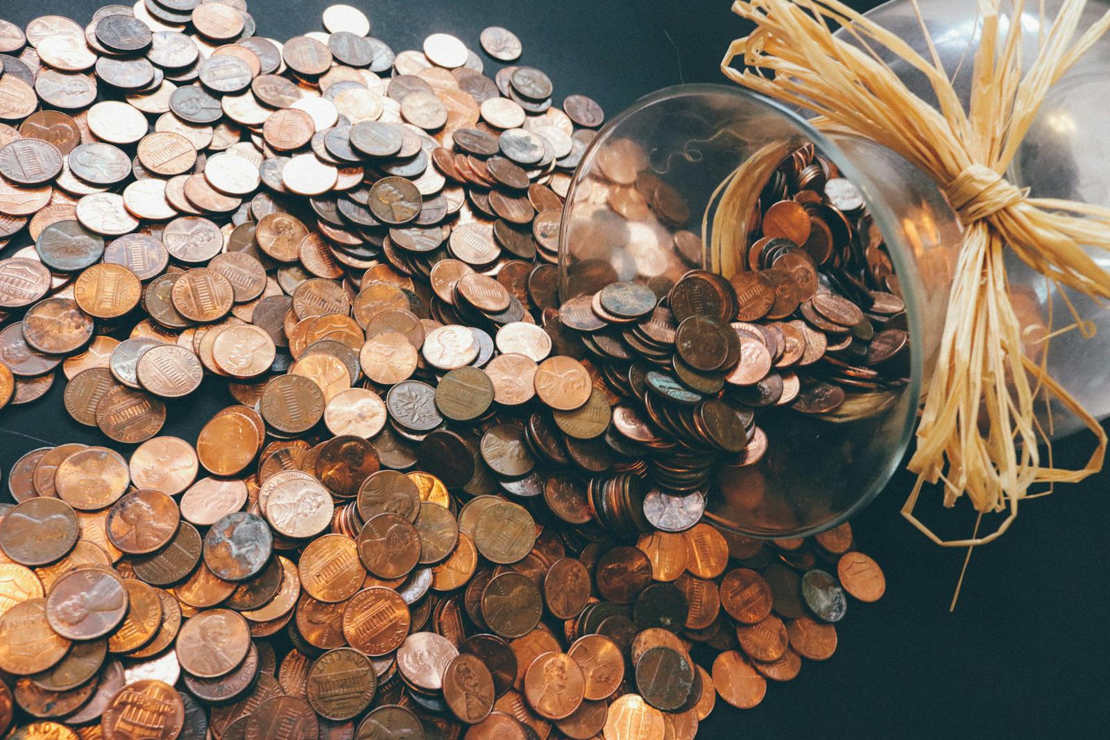 How to Avoid Online Scams – Updated Guidance for 2025 Spilled jar of pennies creating a pattern of coins representing savings and finance.
