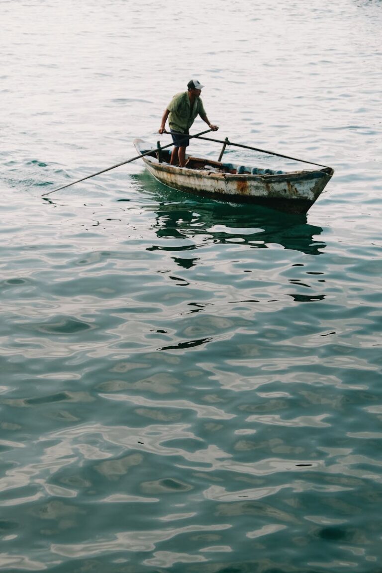 A fisherman navigates a rustic boat in the serene waters of Rạch Giá, Kien Giang, Vietnam.