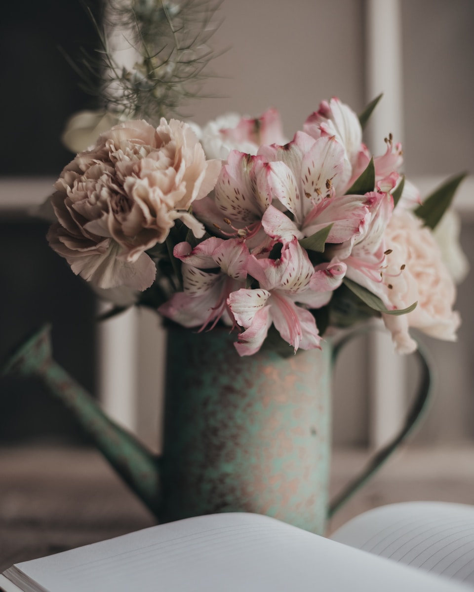 A bouquet of flowers in a vase next to an open book
