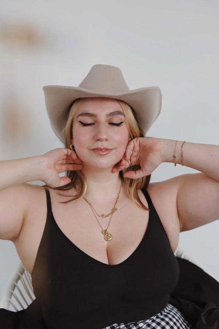 Woman in black spaghetti strap top wearing white cowboy hat