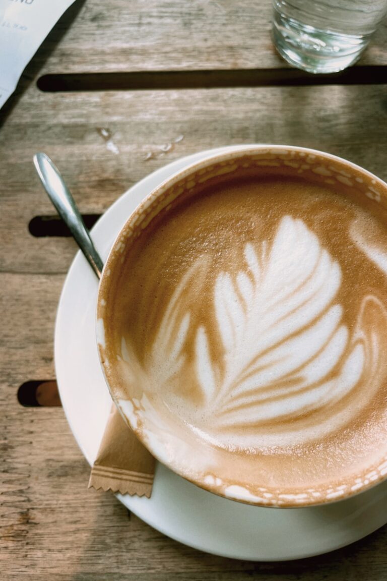 A cup of cappuccino on a saucer with a spoon
