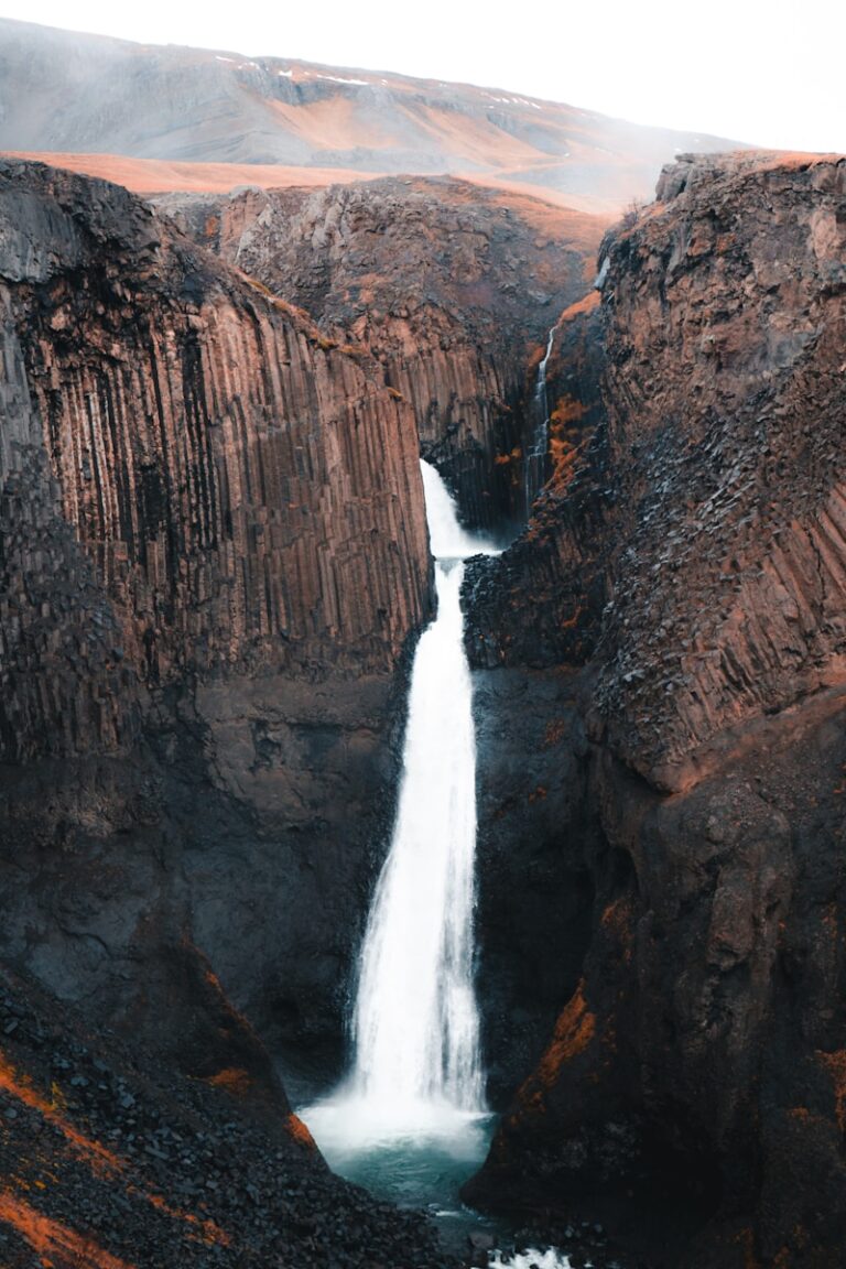 A tall waterfall cascades through a rocky canyon.