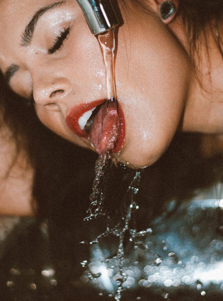 A close-up shot of a woman drinking fresh water from a flowing faucet.