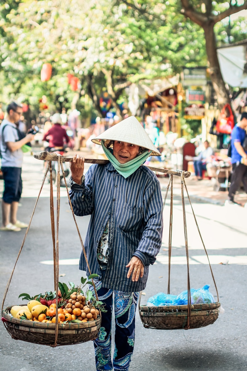 Long An : A Season That Rises With the Water Woman in blue and white stripe dress shirt wearing brown straw hat standing in front of with with with with