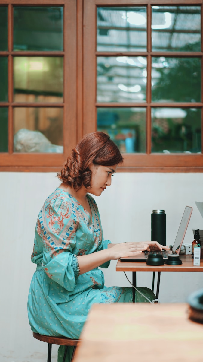 A woman in green and white floral long sleeve shirt using computer