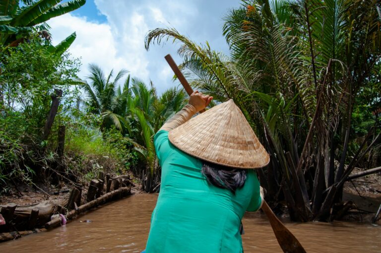 woman in green shirt and brown straw hat sitting on brown wooden dock during daytime