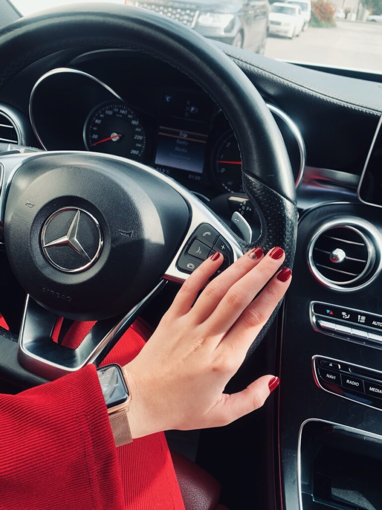 A young women holding black mercedes benz steering wheel