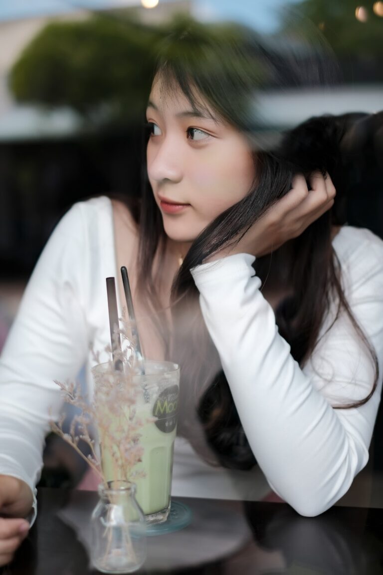 Woman in white long sleeve shirt holding clear drinking glass