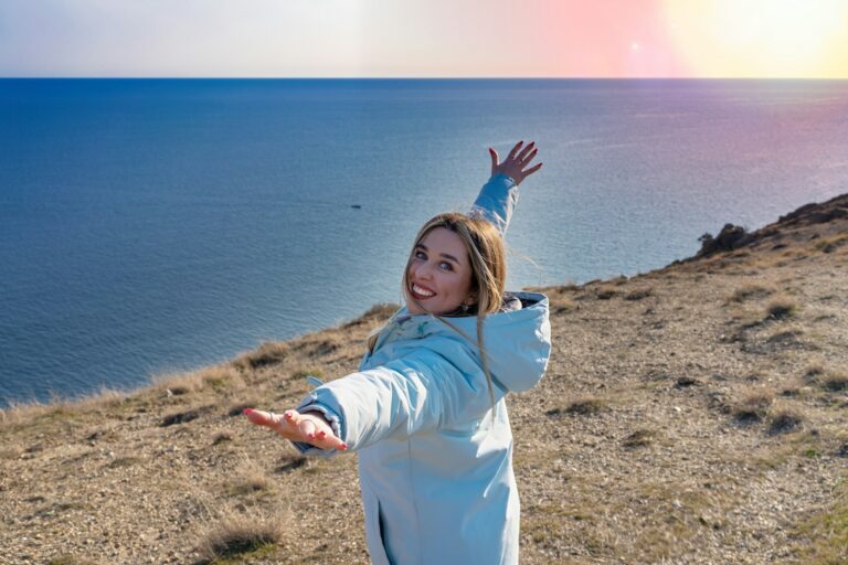 A woman standing on top of a hill near the ocean