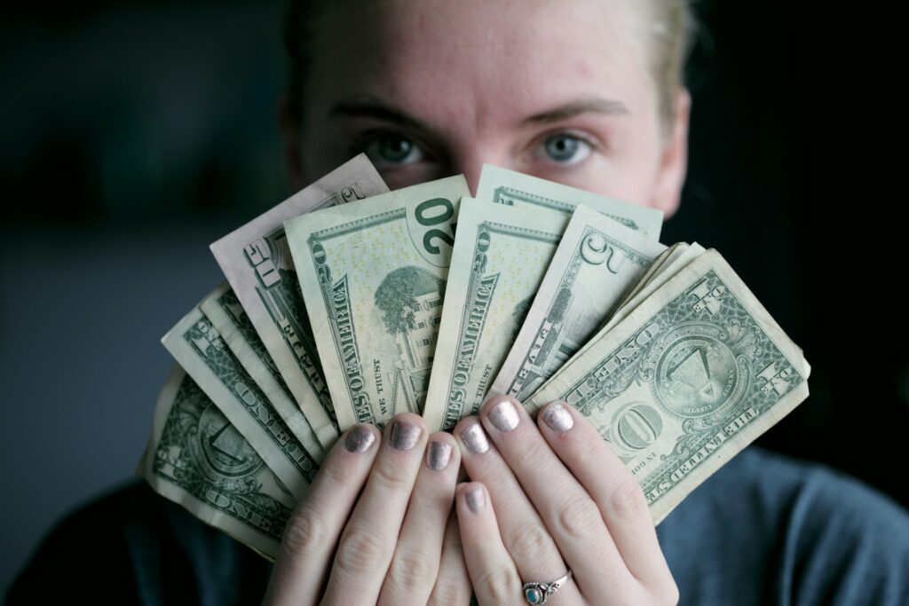 A woman holding fan of U.S. dollars banknote