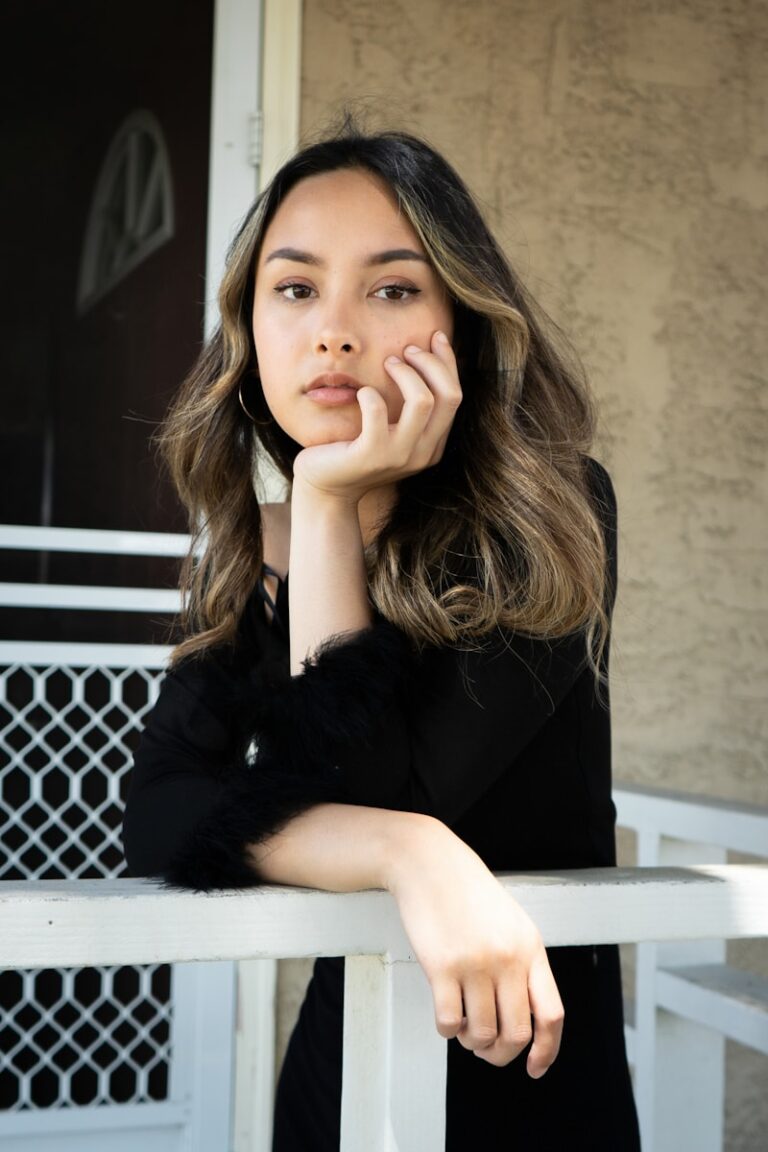 A young girl sitting next to a white railing