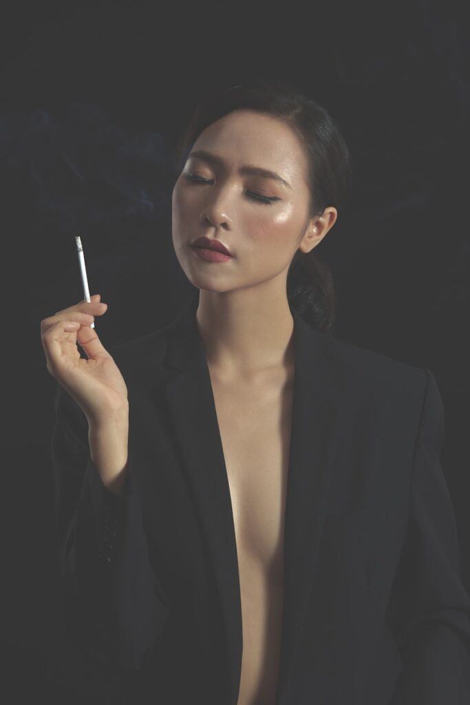 A woman in black blazer holding cigarette stick