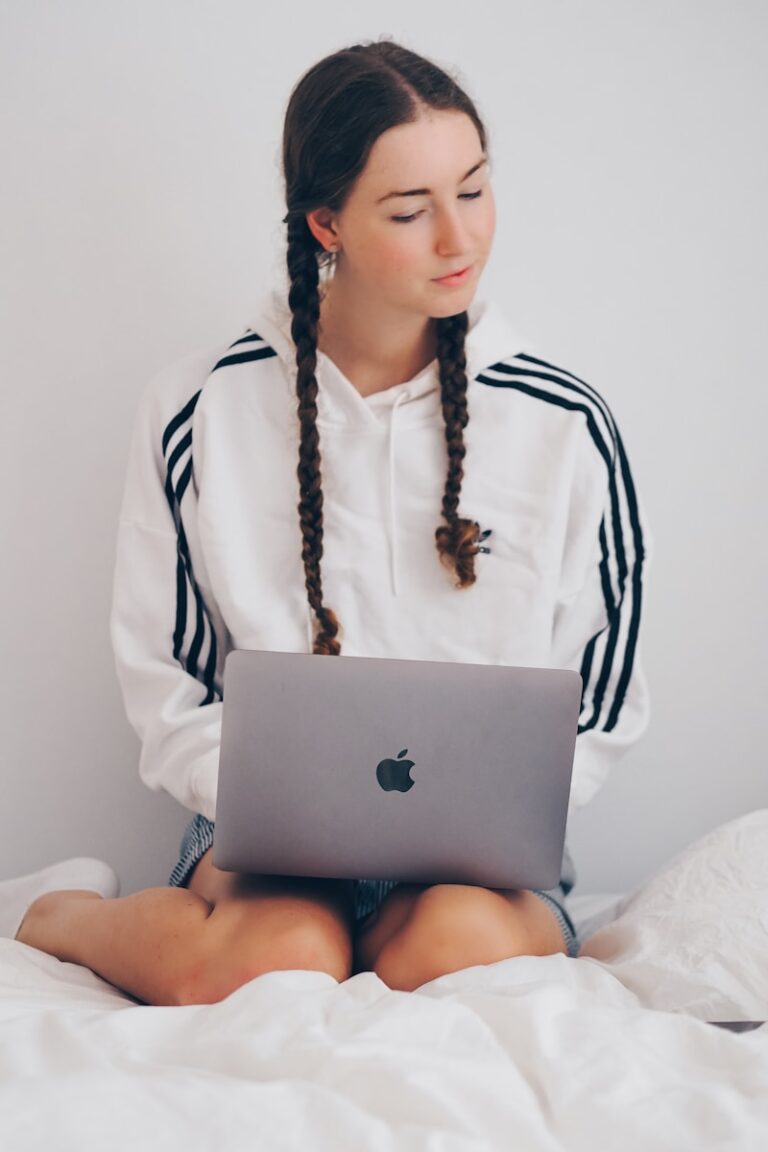 A young woman in white and black long sleeve shirt using silver macbook