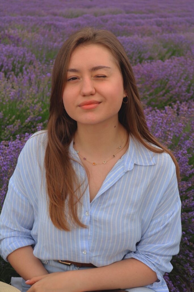A woman standing in front of a field of purple flowers