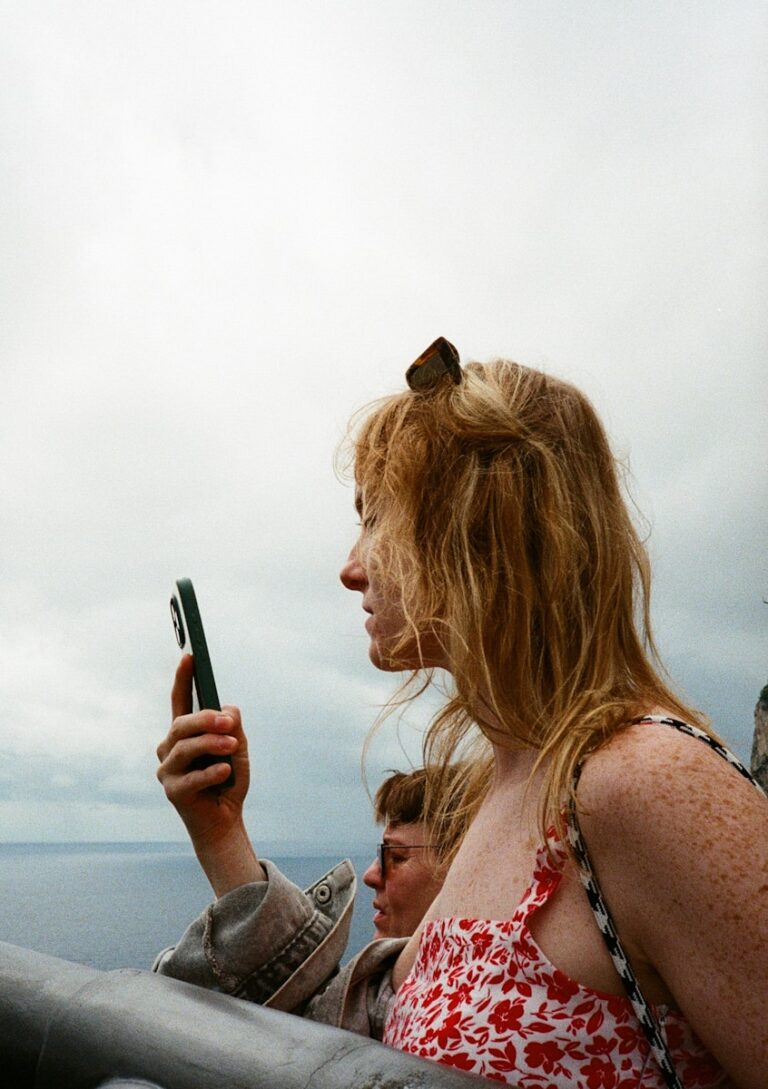 Woman looking at phone with ocean background